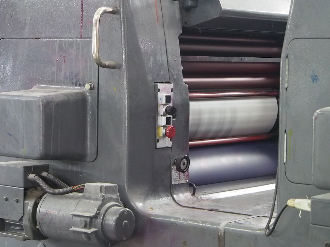 Detailed view of an industrial printing machine showcasing parts and rollers in action.
